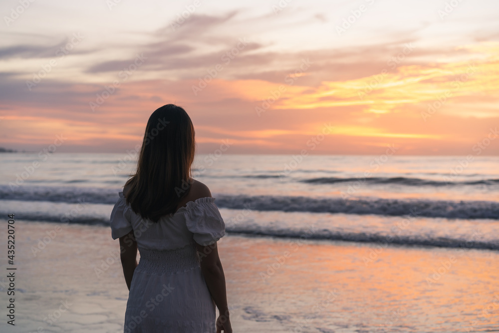 Lonely young asian woman standing on the beach at sunset Lonely young asian woman standing on the beach at sunset