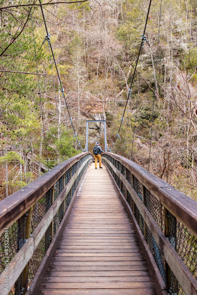 Mountaineer walking on a wooden suspension bridge Mountaineer walking on a wooden suspension bridge