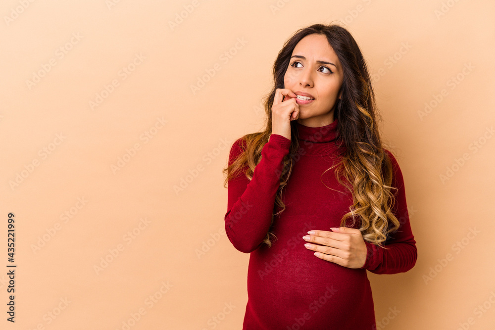 Young mexican pregnant woman isolated on beige background relaxed thinking about something looking at a copy space. Young mexican pregnant woman isolated on beige background relaxed thinking about something looking at a copy space.