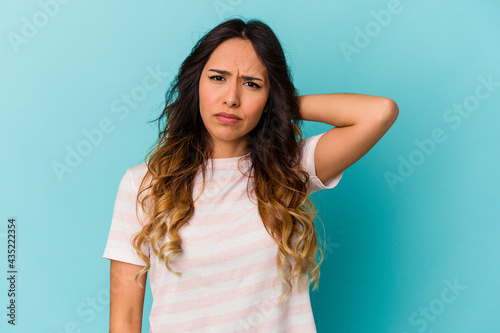 Young mexican woman isolated on blue background suffering neck pain due to sedentary lifestyle. © Asier