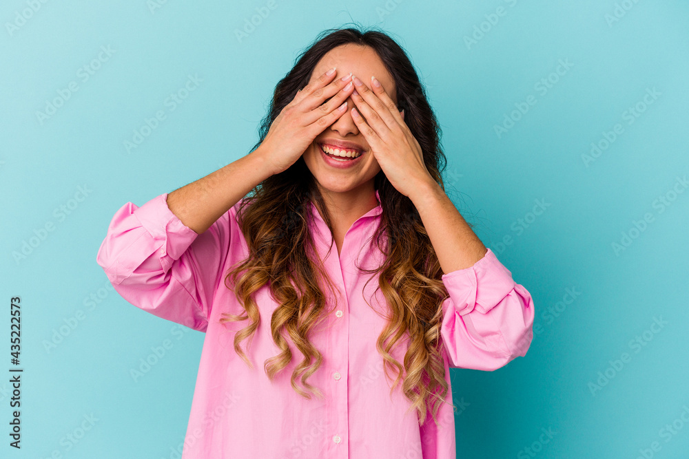 Young mexican woman isolated on blue background covers eyes with hands, smiles broadly waiting for a surprise. Young mexican woman isolated on blue background covers eyes with hands, smiles broadly waiting for a surprise.