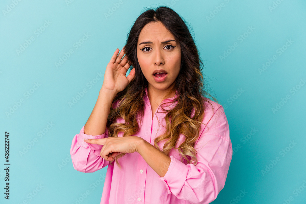 Young mexican woman isolated on blue background trying to listening a gossip. Young mexican woman isolated on blue background trying to listening a gossip.