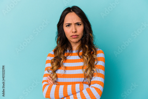 Young mexican woman isolated on blue background blows cheeks, has tired expression. Facial expression concept.