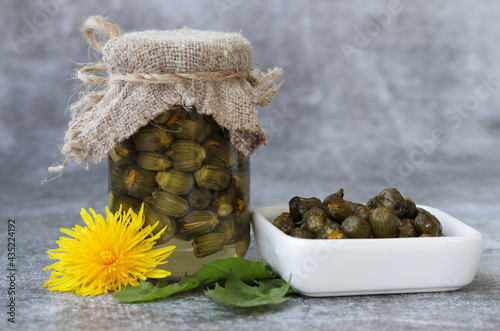 Foto False capers made from ypung dandelion buds in glass jar.