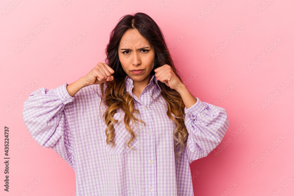 Young mexican woman isolated on pink background throwing a punch, anger, fighting due to an argument, boxing. Young mexican woman isolated on pink background throwing a punch, anger, fighting due to an argument, boxing.