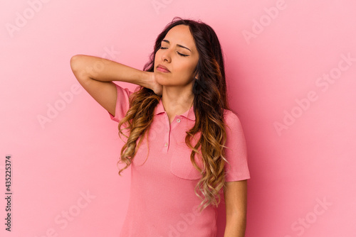 Young mexican woman isolated on pink background having a neck pain due to stress  massaging and touching it with hand.