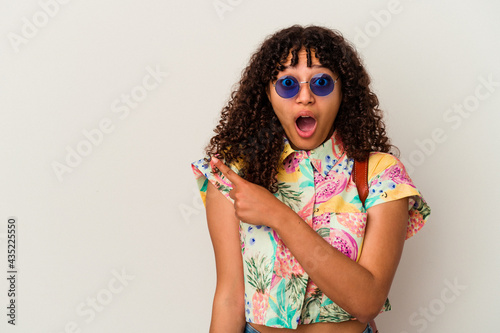 Young mixed race woman wearing sunglasses taking a vacation isolated pointing to the side