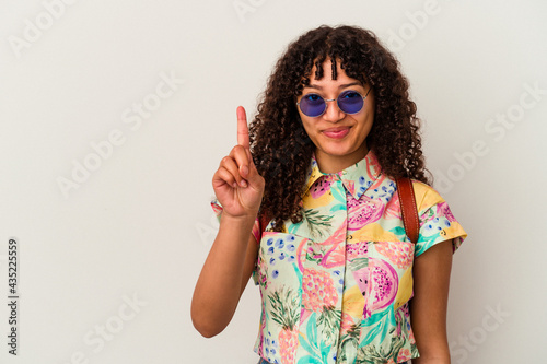 Young mixed race woman wearing sunglasses taking a vacation isolated showing number one with finger.