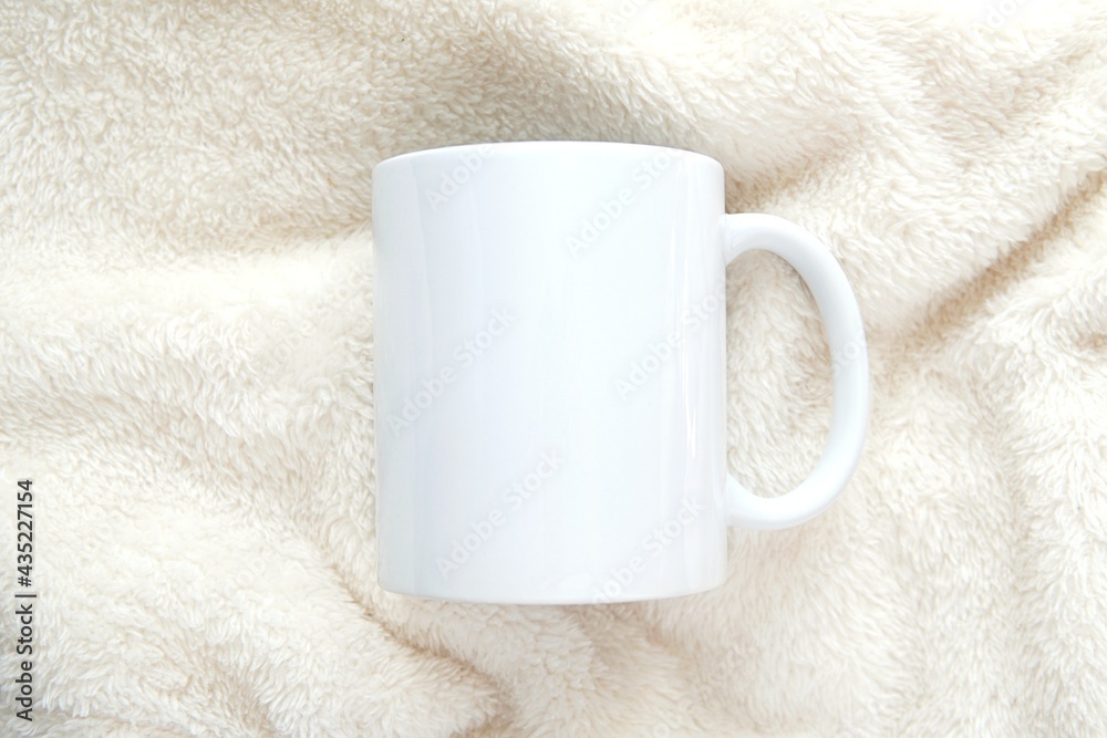 White coffee mug mockup on soft white blanket for feminine or kids design presentation. White coffee mug mockup on soft white blanket for feminine or kids design presentation.