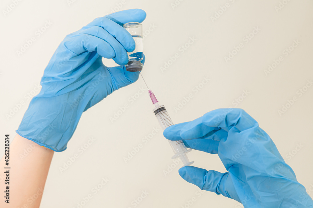 coronavirus vaccine in blue gloves holding holding syringe and bottle with vaccine for covid-19 cure. The weapons used to fight the coronavirus are vaccines and syringes in the hands of doctors.