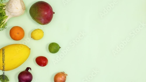 Healthy fresh fruits and vegetables make creative pattern on light green background. Stop motion