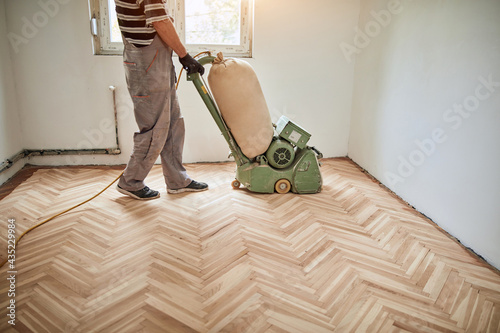 фотографія Repairman restoring parquet with a sanding machine.
