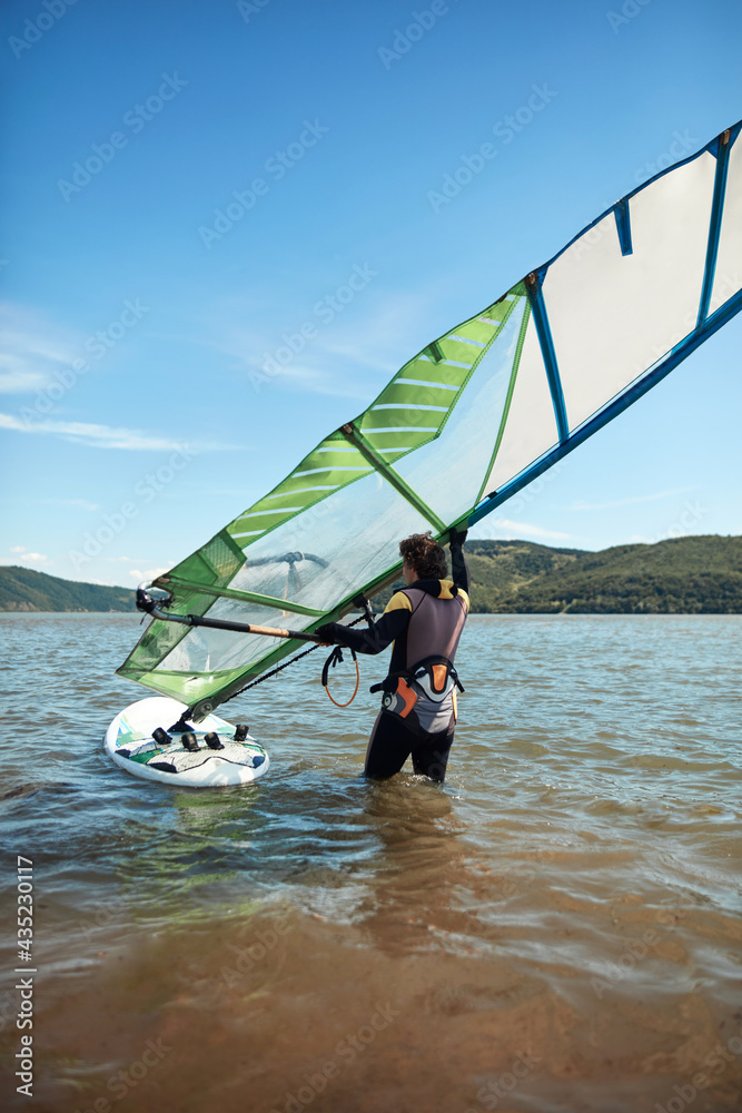 Naklejka premium Windsurfer surfing on a windy summertime day at the river.