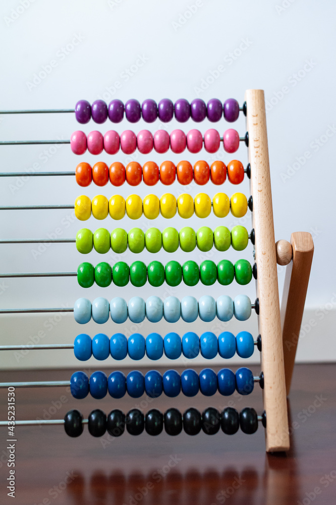 Multi-colored designer background. Calculating Colorful wooden rainbow abacus for number calculation. Close up wooden abacus on white background. Mathematics learning concept. Rainbow colors
