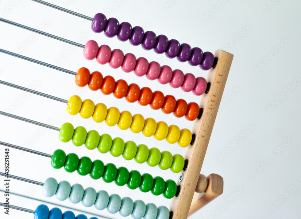 Multi-colored designer background. Calculating Colorful wooden rainbow abacus for number calculation. Close up wooden abacus on white background. Mathematics learning concept. Rainbow colors