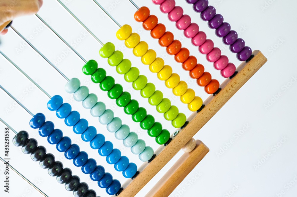 Multi-colored designer background. Calculating Colorful wooden rainbow abacus for number calculation. Close up wooden abacus on white background. Mathematics learning concept. Rainbow colors