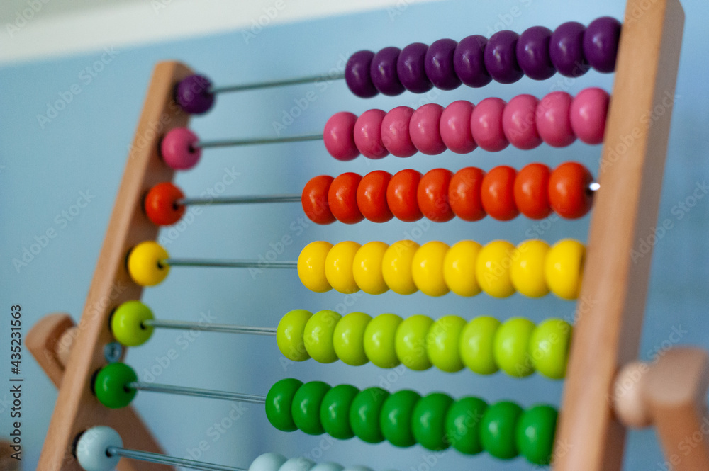 Multi-colored designer background. Calculating Colorful wooden rainbow abacus for number calculation. Close up wooden abacus on white background. Mathematics learning concept. Rainbow colors