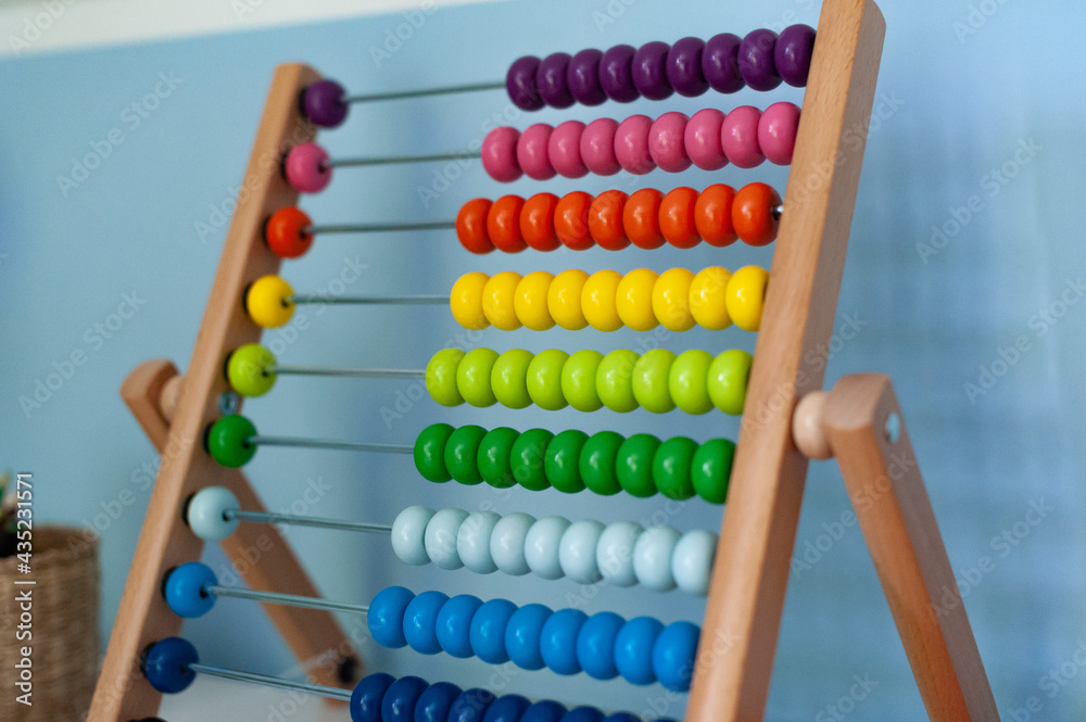 Multi-colored designer background. Calculating Colorful wooden rainbow abacus for number calculation. Close up wooden abacus on white background. Mathematics learning concept. Rainbow colors
