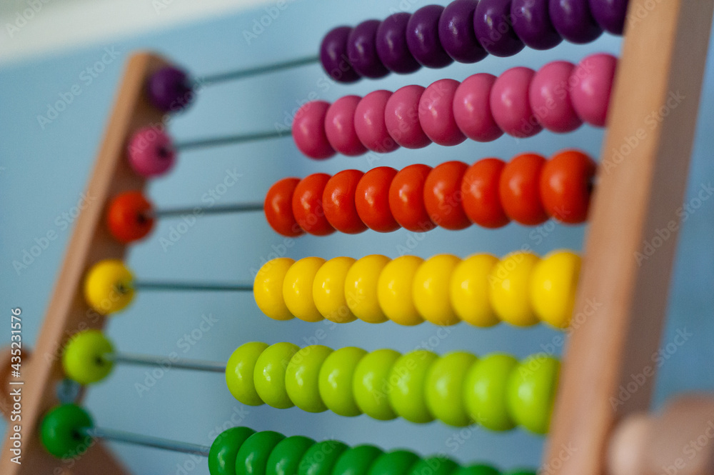 Multi-colored designer background. Calculating Colorful wooden rainbow abacus for number calculation. Close up wooden abacus on white background. Mathematics learning concept. Rainbow colors