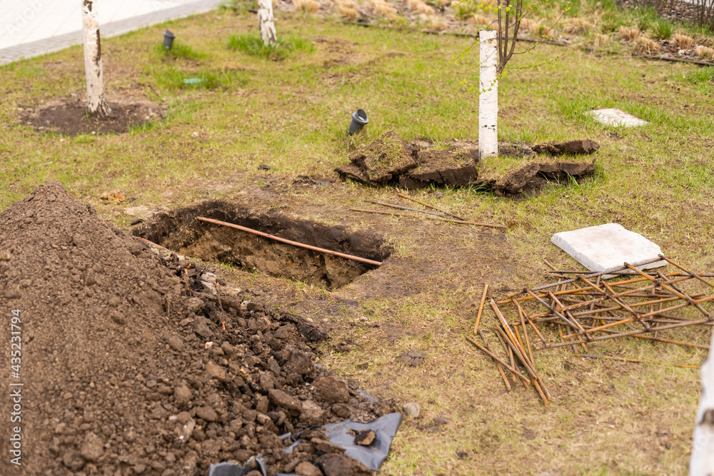 A landscape worker digging a trench during an irrigation system installation project in a yard by a quiet residential street A landscape worker digging a trench during an irrigation system installation project in a yard by a quiet residential street