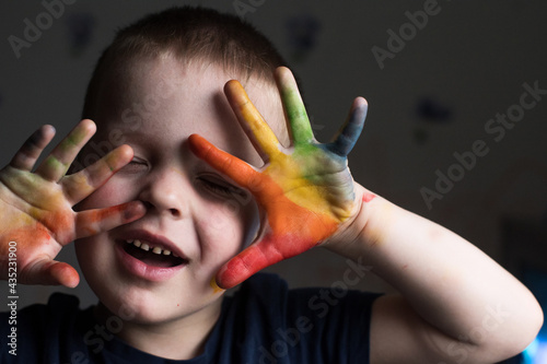 a little boy shows his rainbow-colored hands. the child drew a rainbow on his hands