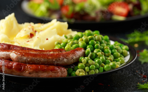 Pork Chipolata sausages with home cooked mashed potato and green peas photo