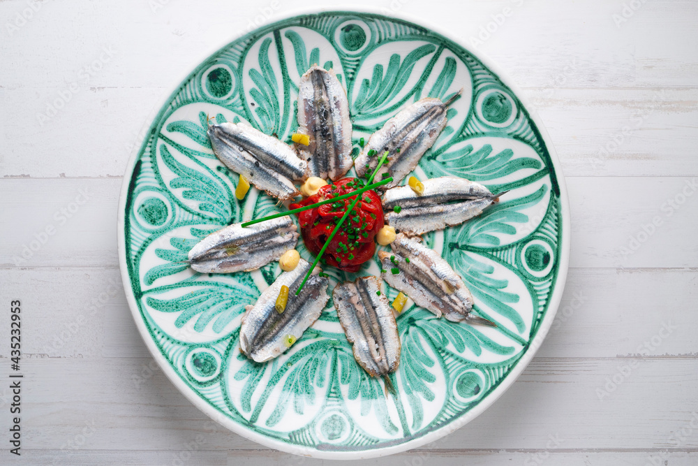 Plate of anchovies with roasted peppers and piparras. Traditional Spanish tapa served on a plate of the Andalusian culture.