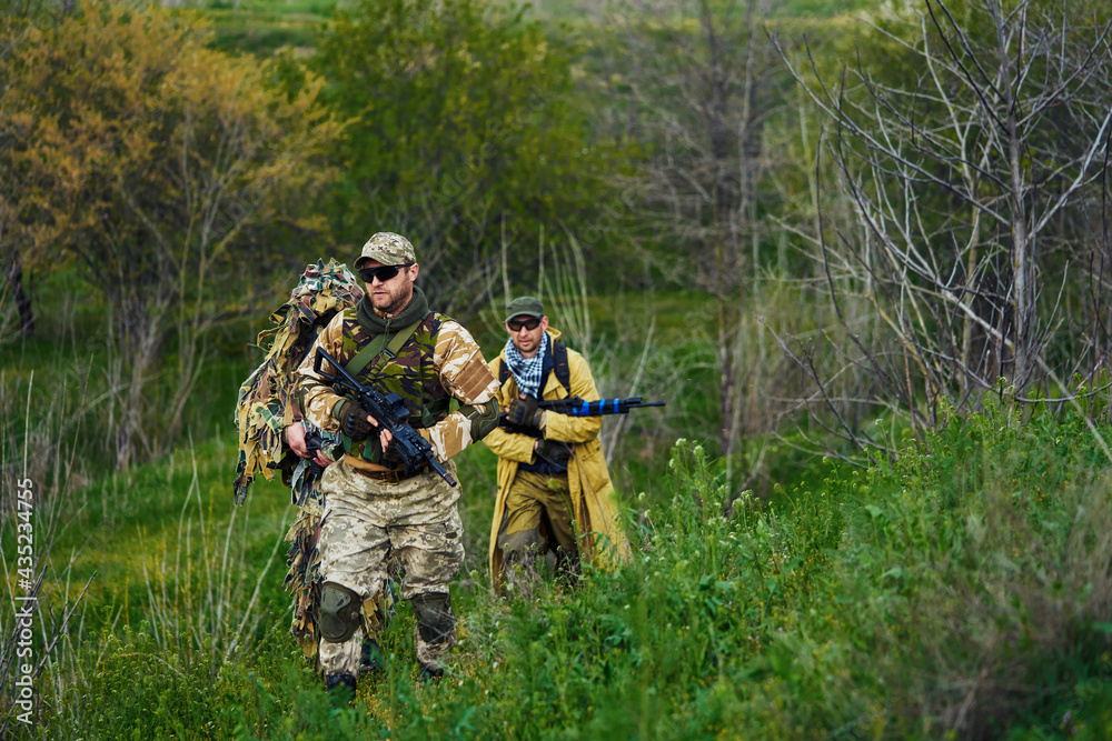 Airsoft players with weapons in their hands are walking in the forest Airsoft players with weapons in their hands are walking in the forest