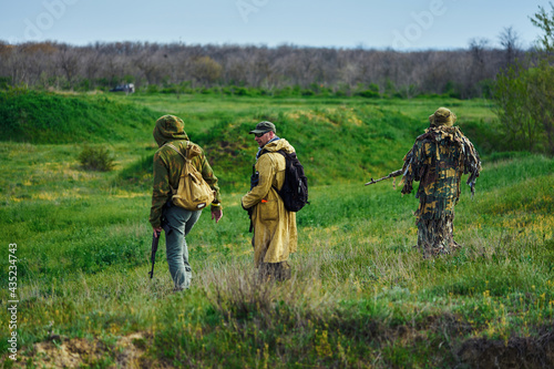 Airsoft players with weapons in their hands are walking along the field