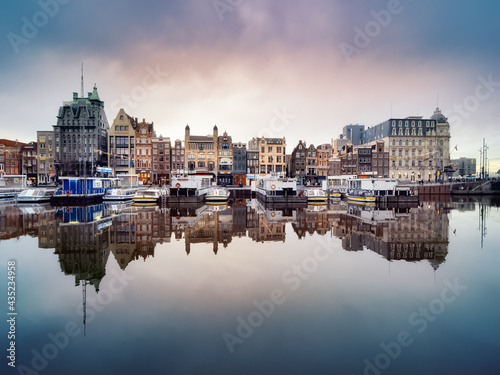Fotografía Reflection of historic canal houses and tourist canal boats in the Damrak canal in Amsterdam
