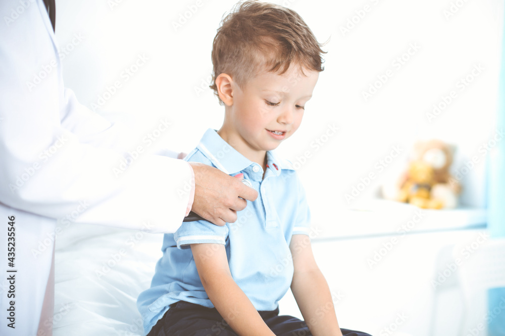 Happy smiling male kid-patient at usual medical inspection. Doctor and young boy in the clinic. Medicine concepts Happy smiling male kid-patient at usual medical inspection. Doctor and young boy in the clinic. Medicine concepts