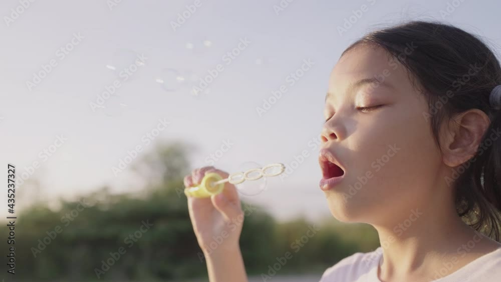 Asian little girl playing with soap bubbles in the midst of nature in the morning and sunlight outdoor Asian little girl playing with soap bubbles in the midst of nature in the morning and sunlight outdoor