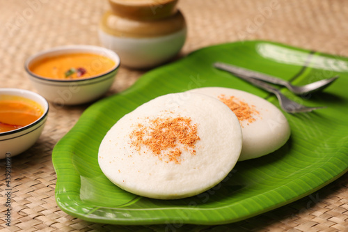 Thatte idli or Plate idly with sambar coconut chutney, chutney podi popular breakfast of Kerala South India Sri Lanka. Healthy steamed rice cakes steaming fermented batter black lentils and rice.