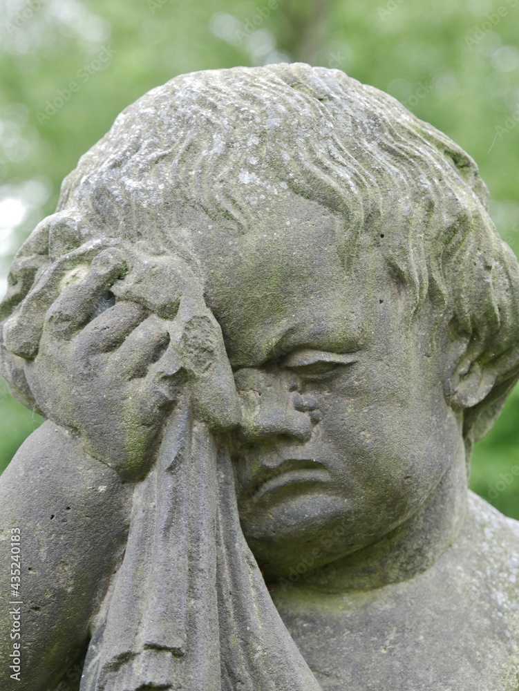 Statue eines weinenden Jungen auf dem Friedhof Statue eines weinenden Jungen auf dem Friedhof