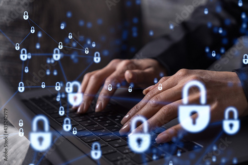 A woman programmer is typing a code on computer to protect a cyber security from hacker attacks and save clients confidential data. Padlock Hologram icons over the typing hands. Formal wear.