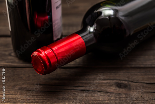 Two bottles of red wine lying on an old wooden table. Close up view, focus on the bottle of red wine