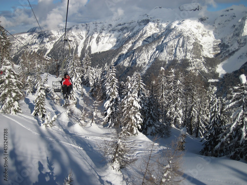 Skier sitting on cable car behind him mountain peaks, mountain landscape