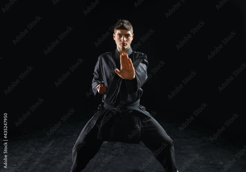 Male karateka, fighter practice in black kimono