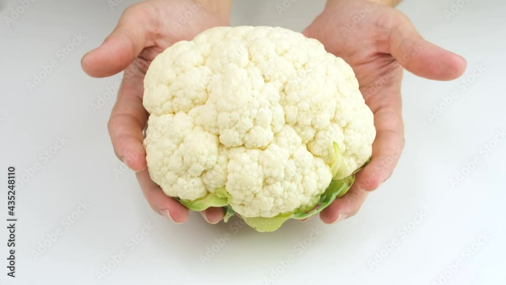 The man's hand slowly moved Cauliflower into on a white background. The man's hand slowly moved Cauliflower into on a white background.
