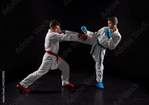 Two karatekas in white kimono and gloves, strike