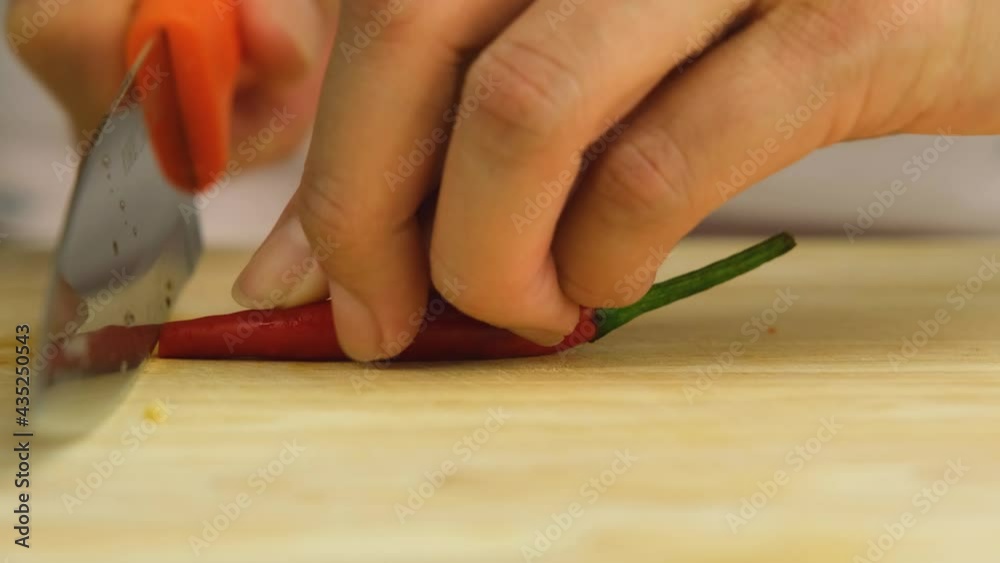 woman's hand is using a knife to cut red chili peppers for cooking. woman's hand is using a knife to cut red chili peppers for cooking.