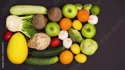 Fresh ripe and healthy fruits and vegetables appear on black table. Stop motion 