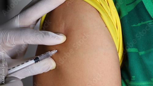 Doctor giving vaccination shot to shoulders. Doctors' hands are wearing rubber gloves and are vaccinated intramuscularly to build immunity to the global coronavirus pandemic. Focus and choose content photo