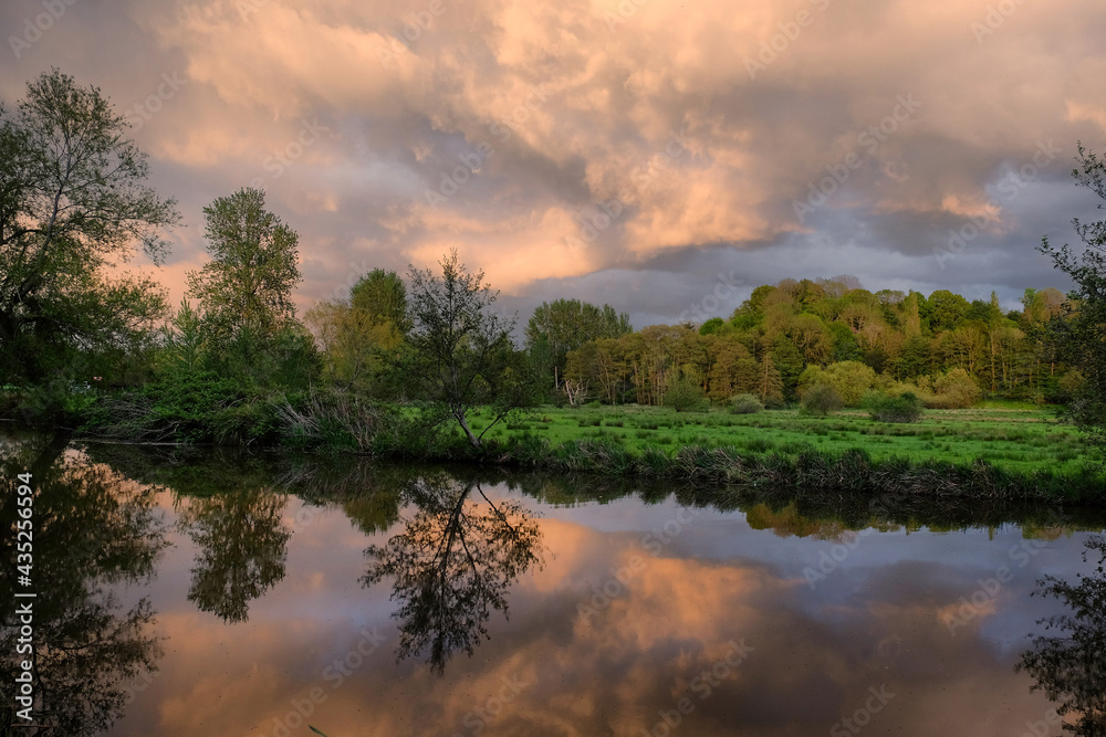 Stormy skies as the sun sets over the River Wey and meadows in Godalming, Surrey, UK