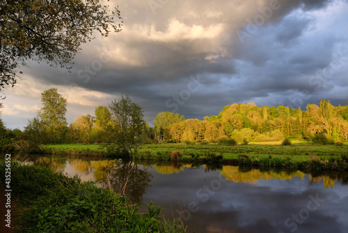 Stormy skies as the sun sets over the River Wey and meadows in Godalming, Surrey, UK