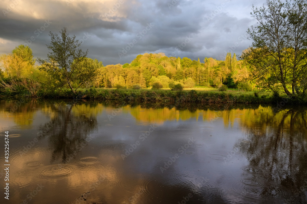 Stormy skies and rain  as the sun sets over the River Wey and meadows in Godalming, Surrey, UK