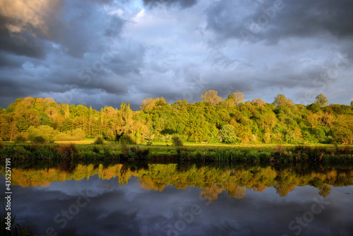 Stormy skies as the sun sets over the River Wey and meadows in Godalming, Surrey, UK