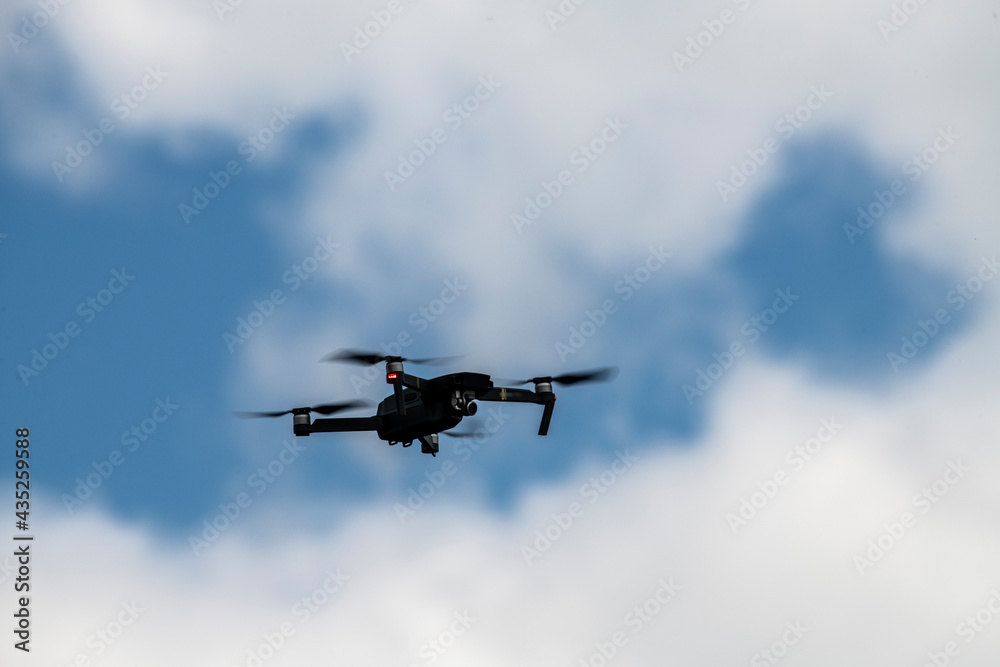 a soaring drone flies above the ground against the background of a blue and white sky a soaring drone flies above the ground against the background of a blue and white sky