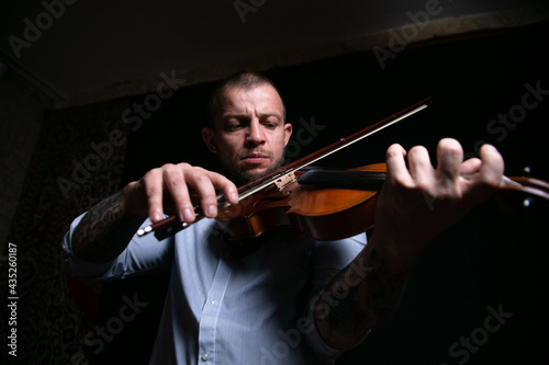 a male violinist masterfully plays the violin in a dark room