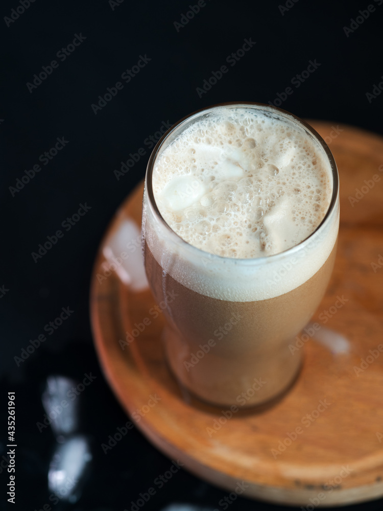 A glass of iced coffee with ice cream on the dark table A glass of iced coffee with ice cream on the dark table